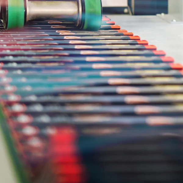 Brochures being folded and sewn on a conveyor